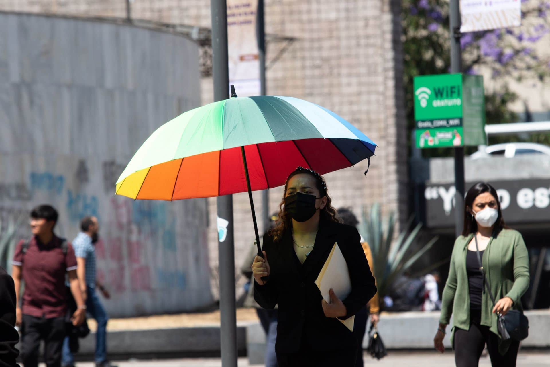 Mujer con cubrebocas se protege de los rayos del sol con su paraguas en la Glorieta de los Insurgentes.