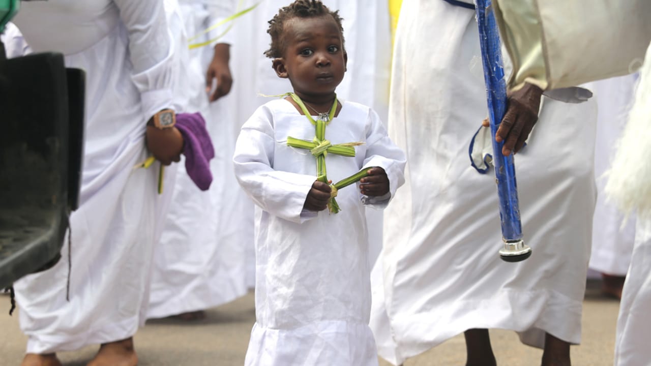 Un niño lleva una hoja de palma en forma de cruz alrededor del cuello en la procesión del Domingo de Ramos, en Lagos, Nigeria