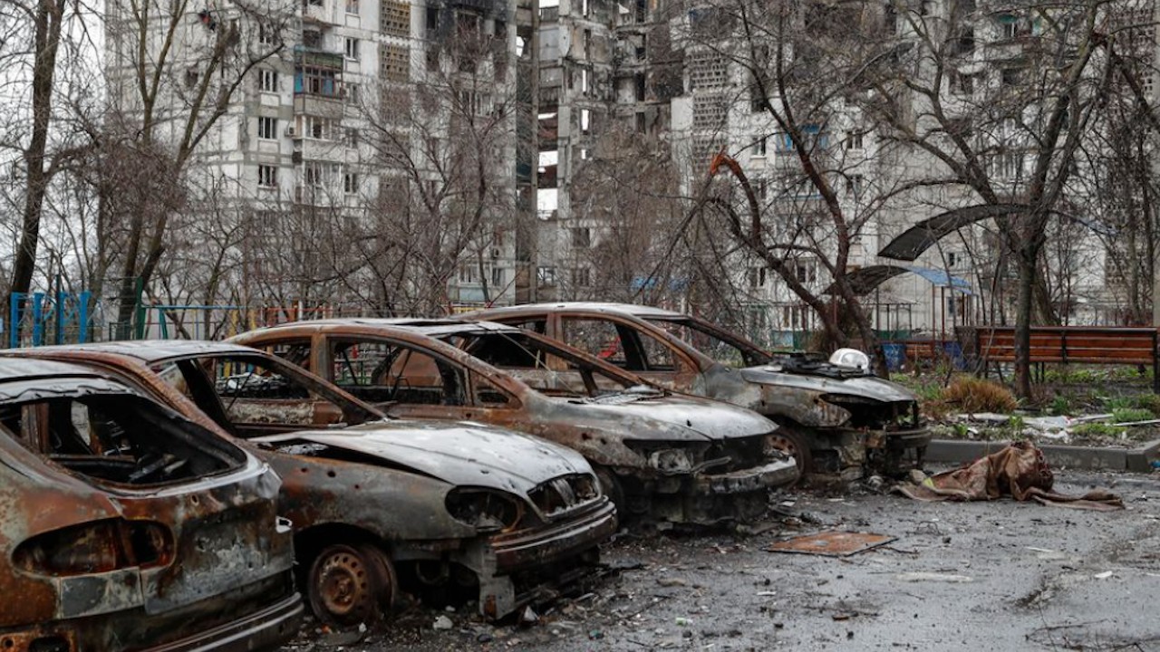 Autos quemados frente a un edificio residencial dañado en el curso del conflicto Ucrania-Rusia en la ciudad portuaria sureña de Mariupol (Reuters)