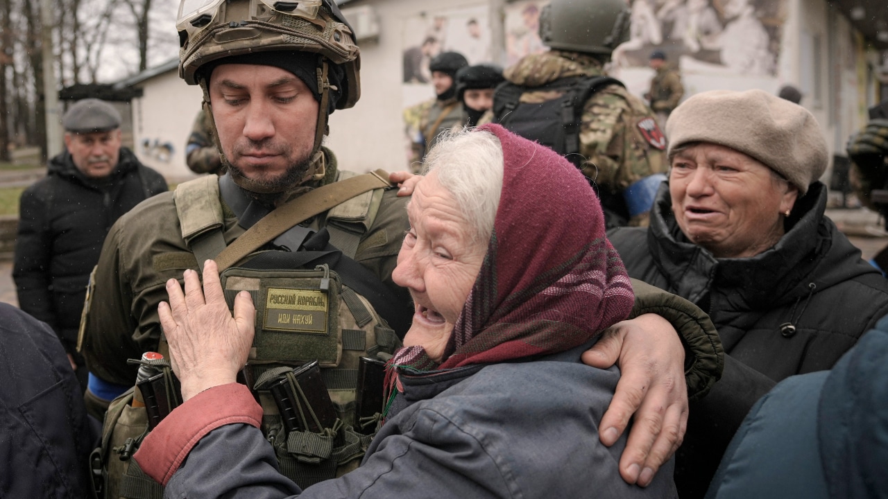 Una mujer abraza a un militar ucraniano después de que un convoy de vehículos militares y de ayuda llegara al suburbio de Bucha, Ucrania