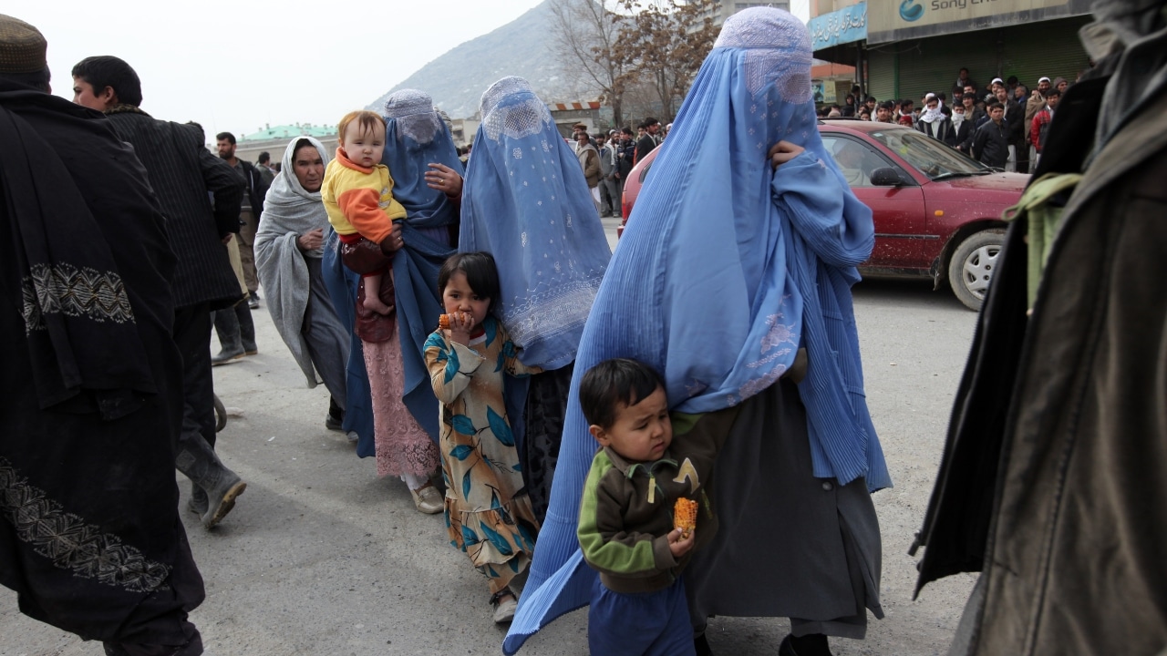 Mujeres afganas vestidas con burkas pasean a sus hijos en el mercado central de Kabul, Afganistán.