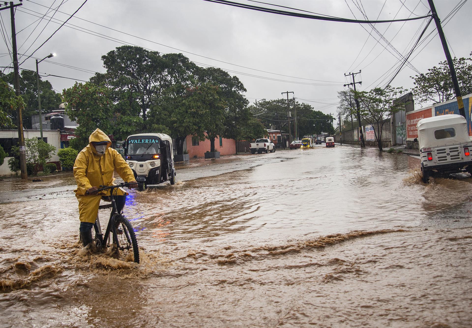 Personas transitan por una avenida inundada en el municipio de Tehuantepec, Oaxaca (EFE) 