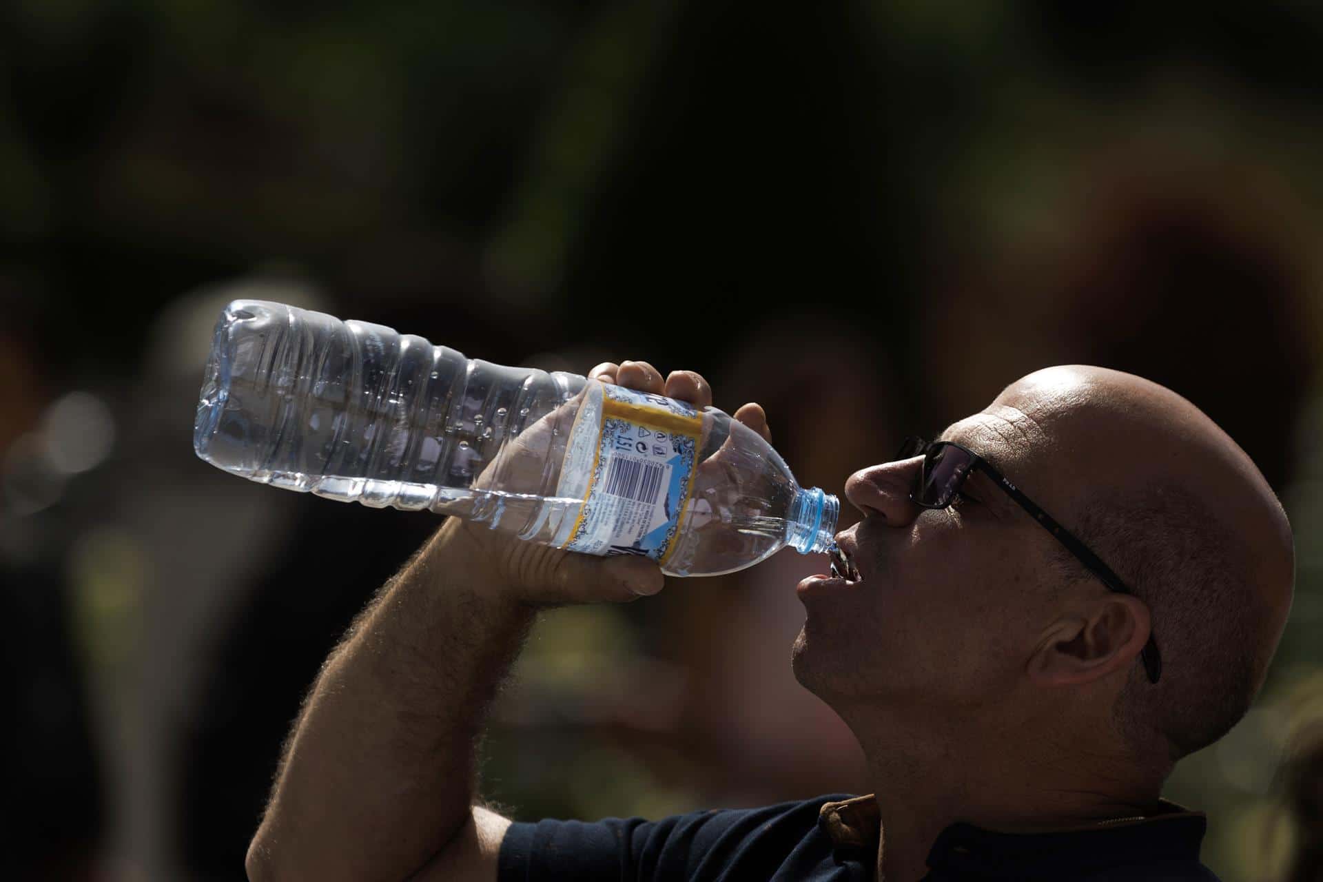 Un turista bebe agua mientras hace fila para entrar al Palacio Real de Madrid, 13 de junio de 2022 (EFE)