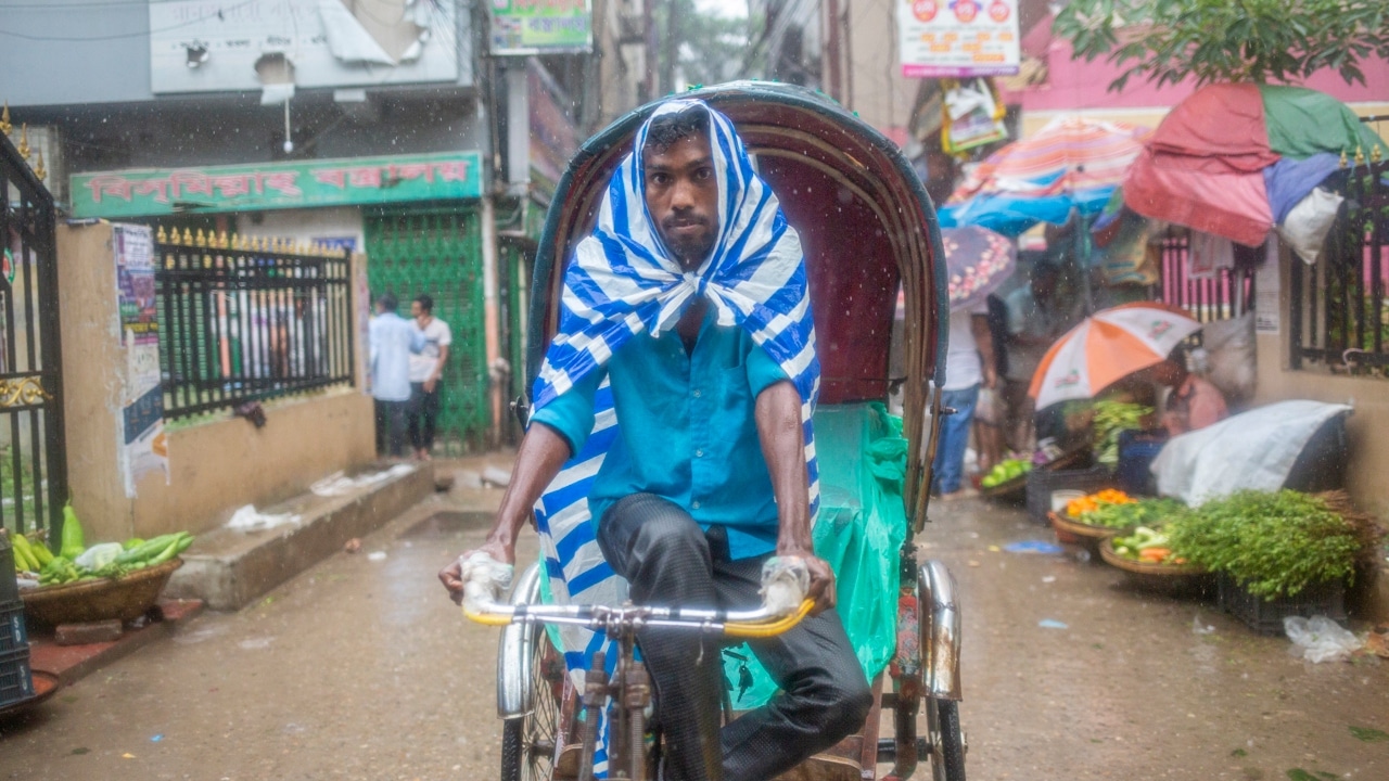 Una persona se protege de la lluvia en Dhaka, Bangladesh, con una bolsa de plástico