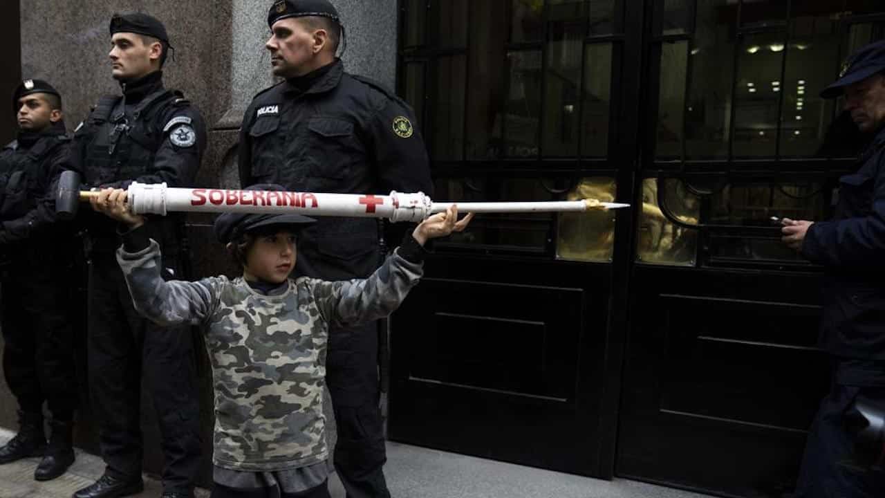 Un niño sostiene una jeringa gigante durante una protesta frente a la Corte Suprema tras suspenderse la vacunación contra COVID-19 para niños (AP)