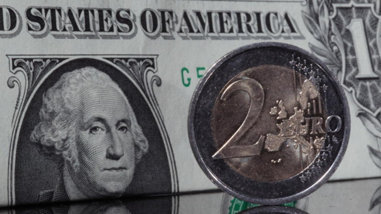 Fotografía que muestra un billete de dólar y una moneda de dos euros
