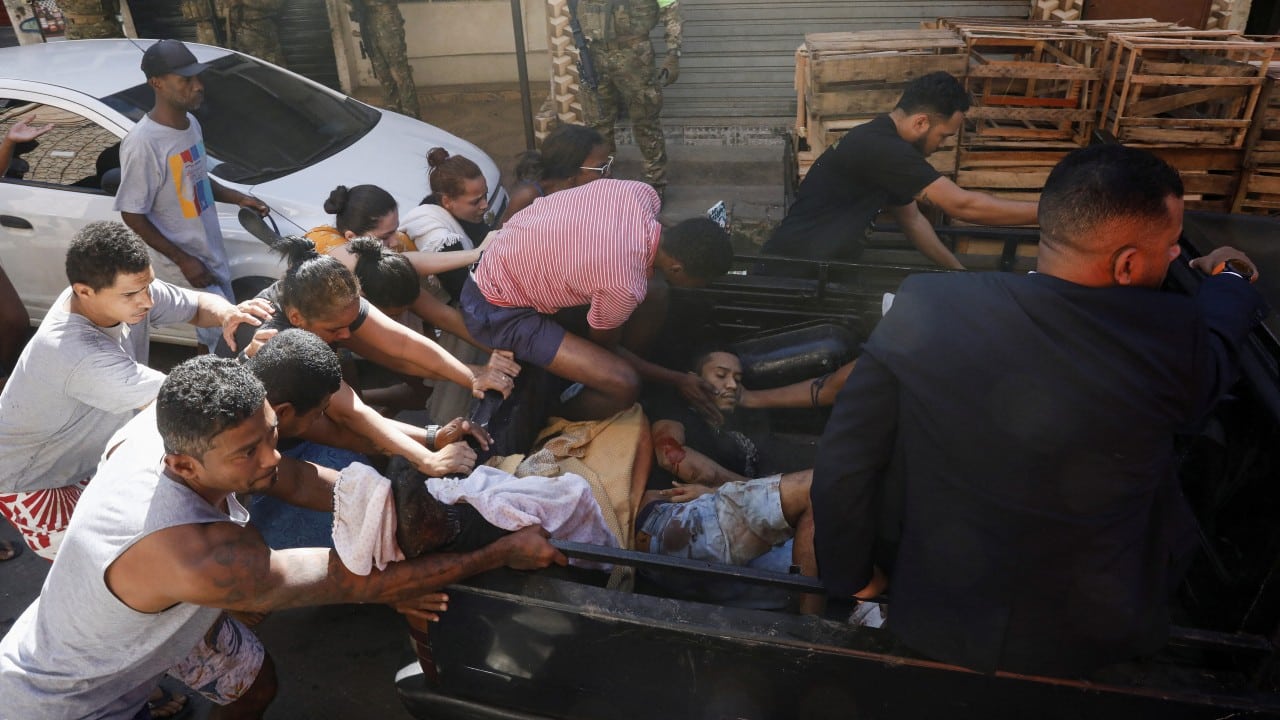 La gente ayuda a un hombre herido durante una operación policial contra bandas de narcotraficantes en el complejo de barrios marginales de Alemao, en Río de Janeiro, Brasil, 21 de julio de 2022 (Reuters)