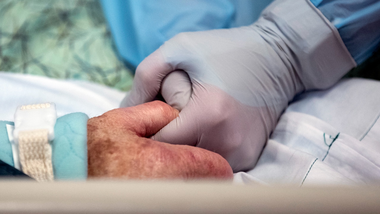 Una enfermera toma de la mano a una paciente con coronavirus ingresada en la UCI de un hospital en Estados Unidos