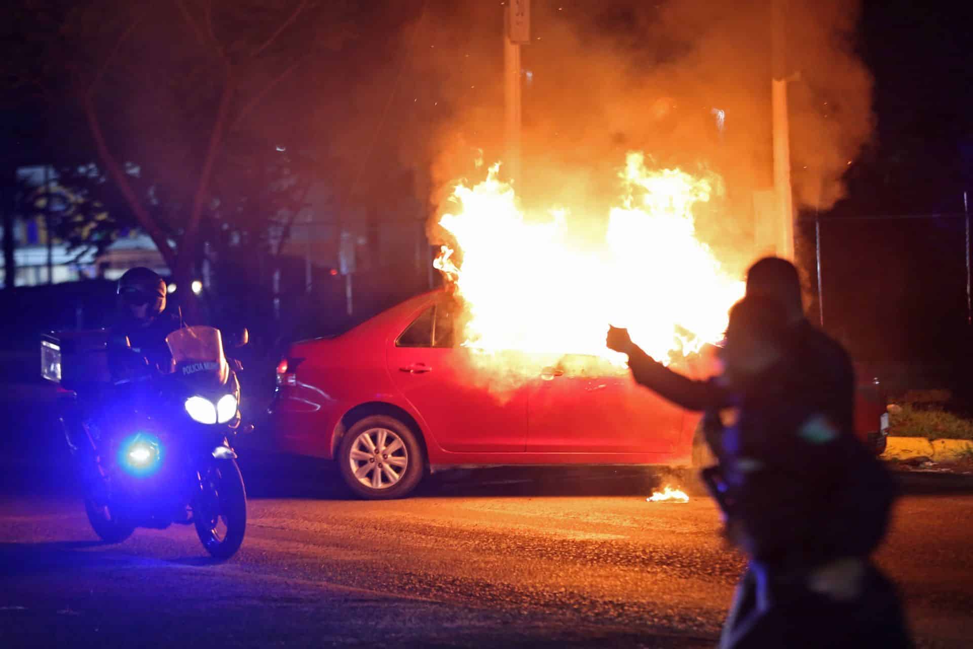 Elementos de la policía de Zapopan atienden los vehículos incendiados por criminales tras el enfrentamiento con el ejército mexicano.