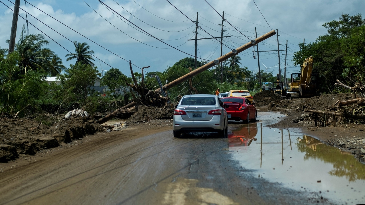 Los autos pasan por debajo de un poste eléctrico caído después del huracán Fiona en Santa Isabel, Puerto Rico.
