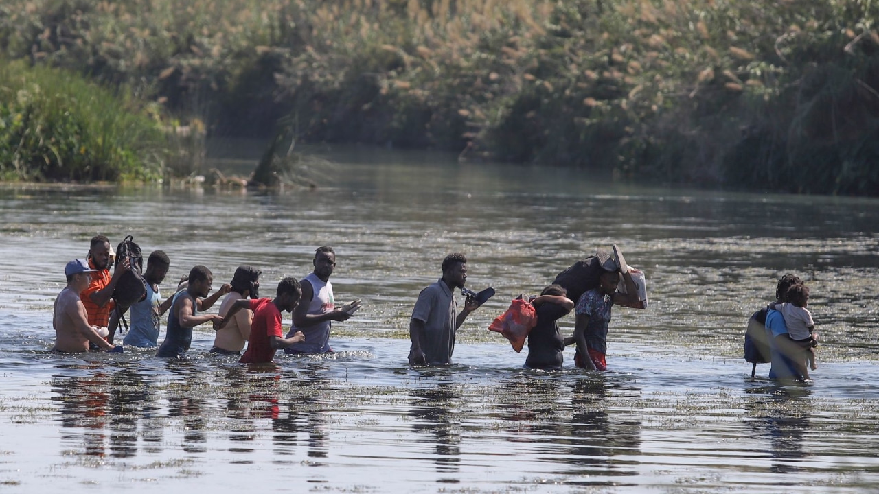 Un grupo de haitianos cruzan el río Bravo.