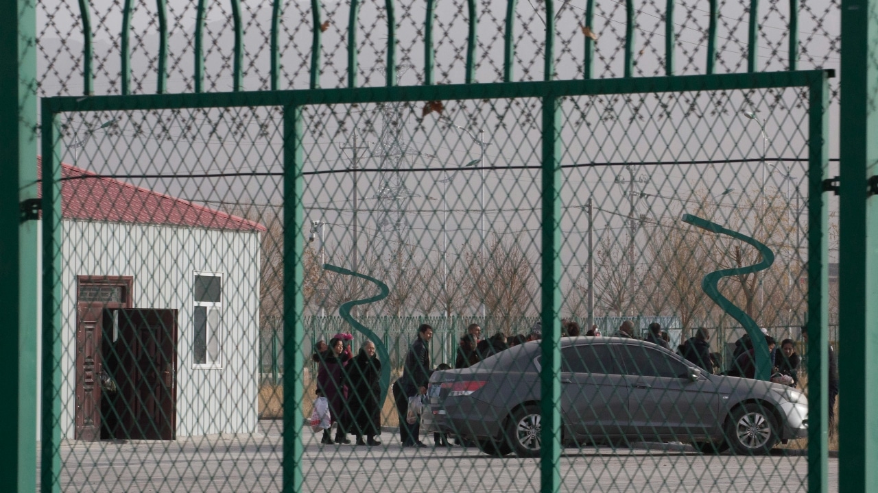 Residentes hacen fila dentro de un centro señalado de ser utilizado para realizar trabajo forzado en la región de Xinjiang.