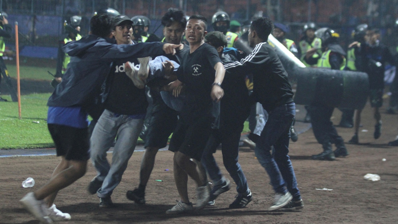 Los partidarios evacuan a un hombre golpeado por gas lacrimógeno disparado por la policía durante los disturbios