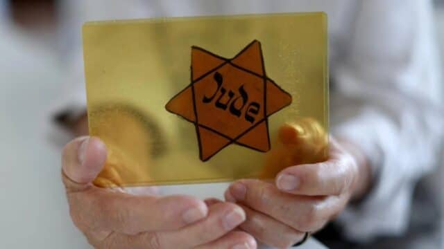 Sobreviviente del Holocausto muestra la insignia que los nazis los obligaban a usar. Foto: AFP